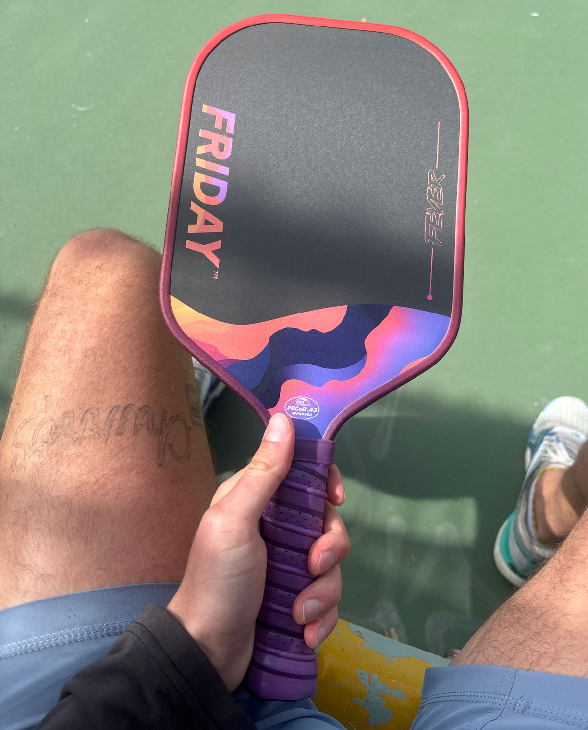 Person holding a colorful pickleball paddle with 'FRIDAY' text on it.