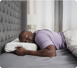 Man sleeping peacefully on a bed in a gray room.