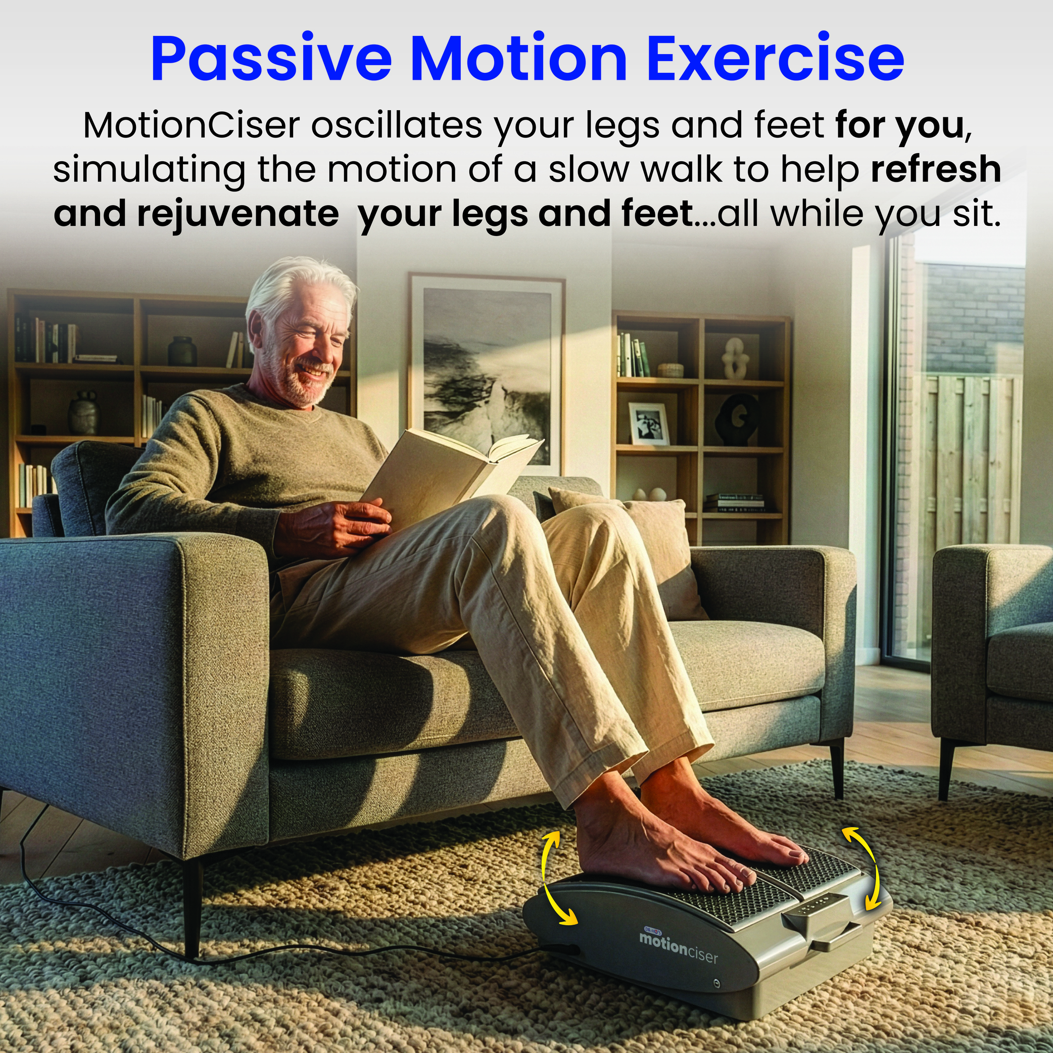 An older man sits on a sofa reading a book with his feet on a passive motion exercise machine.