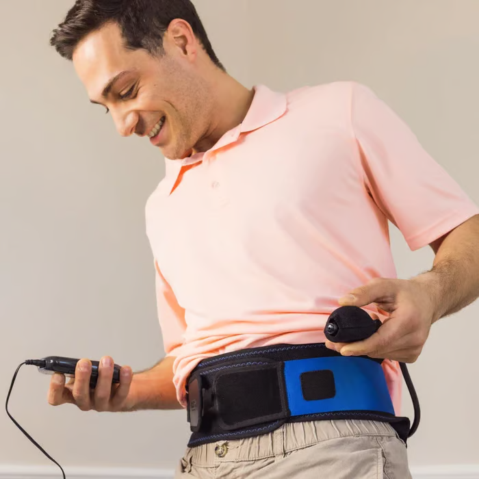 Man wearing a back brace and operating a device with a remote.