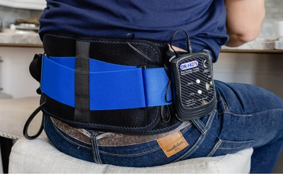 Person wearing a lumbar support belt with an attached electronic device.