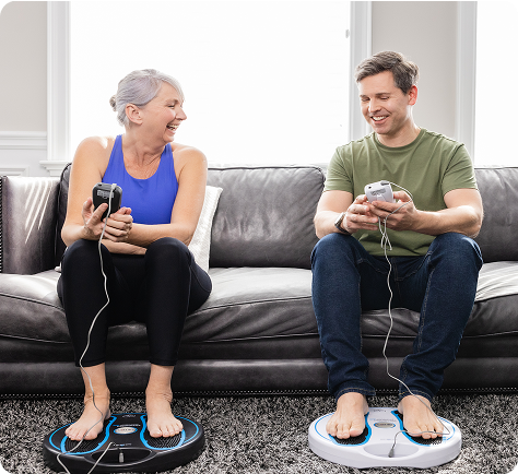 Woman sitting on bed using electronic leg massagers.