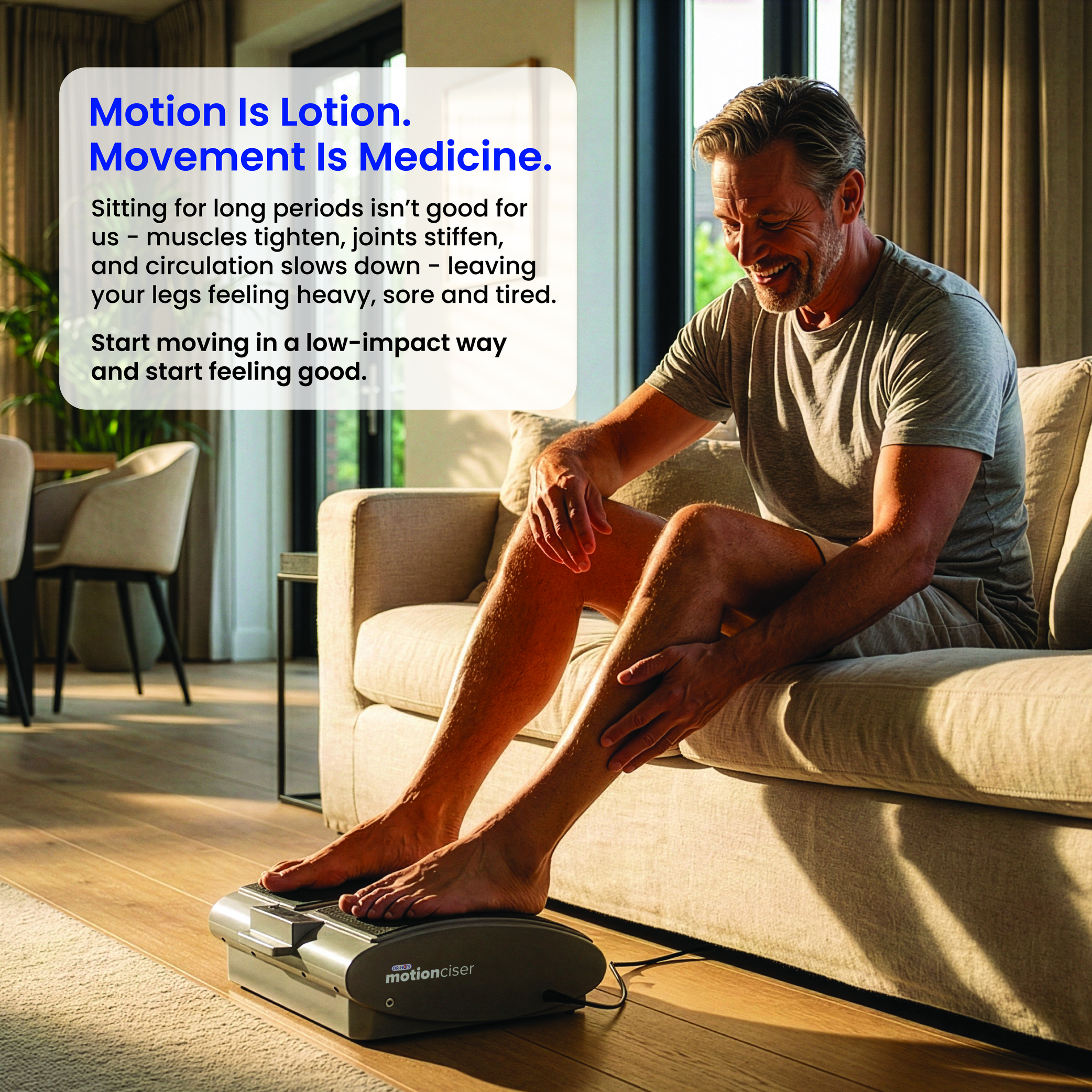 A man sits on a sofa, smiling as he uses a motionciser foot machine and rubs his leg.