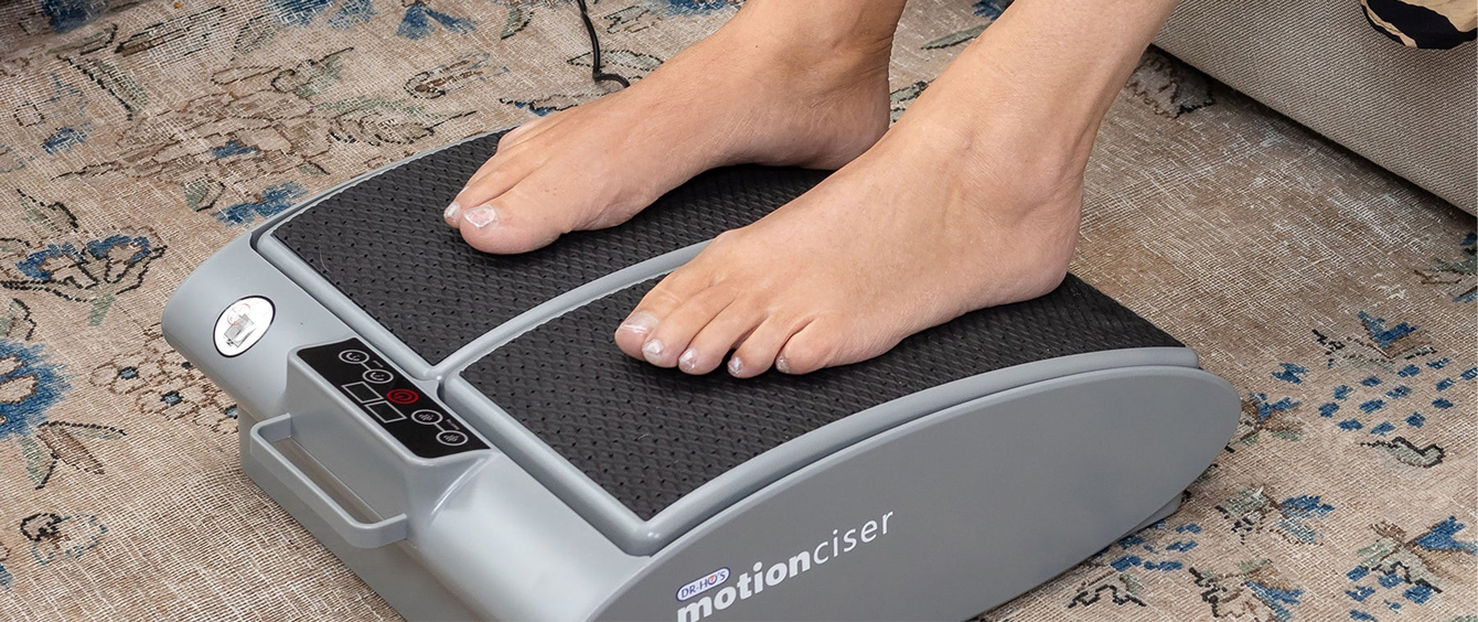 Feet on a foot exercise machine on a patterned rug.