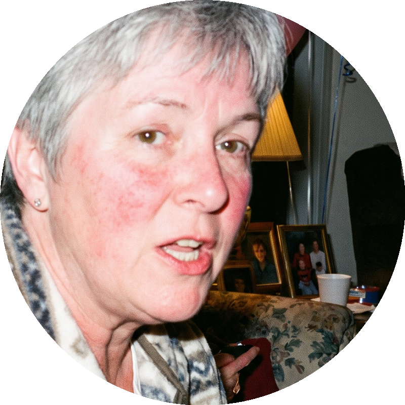 A close-up, circular photo of a woman with short gray hair speaking and looking at the camera.