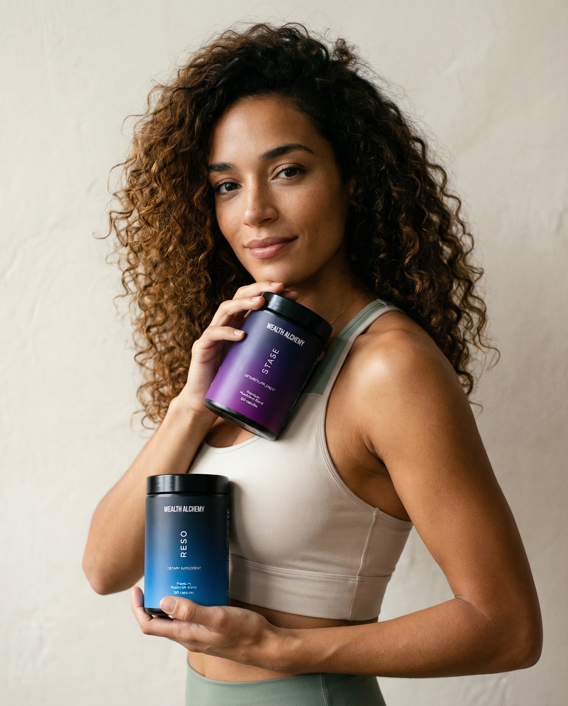A woman with curly hair in a sports bra holds two jars of dietary supplements.