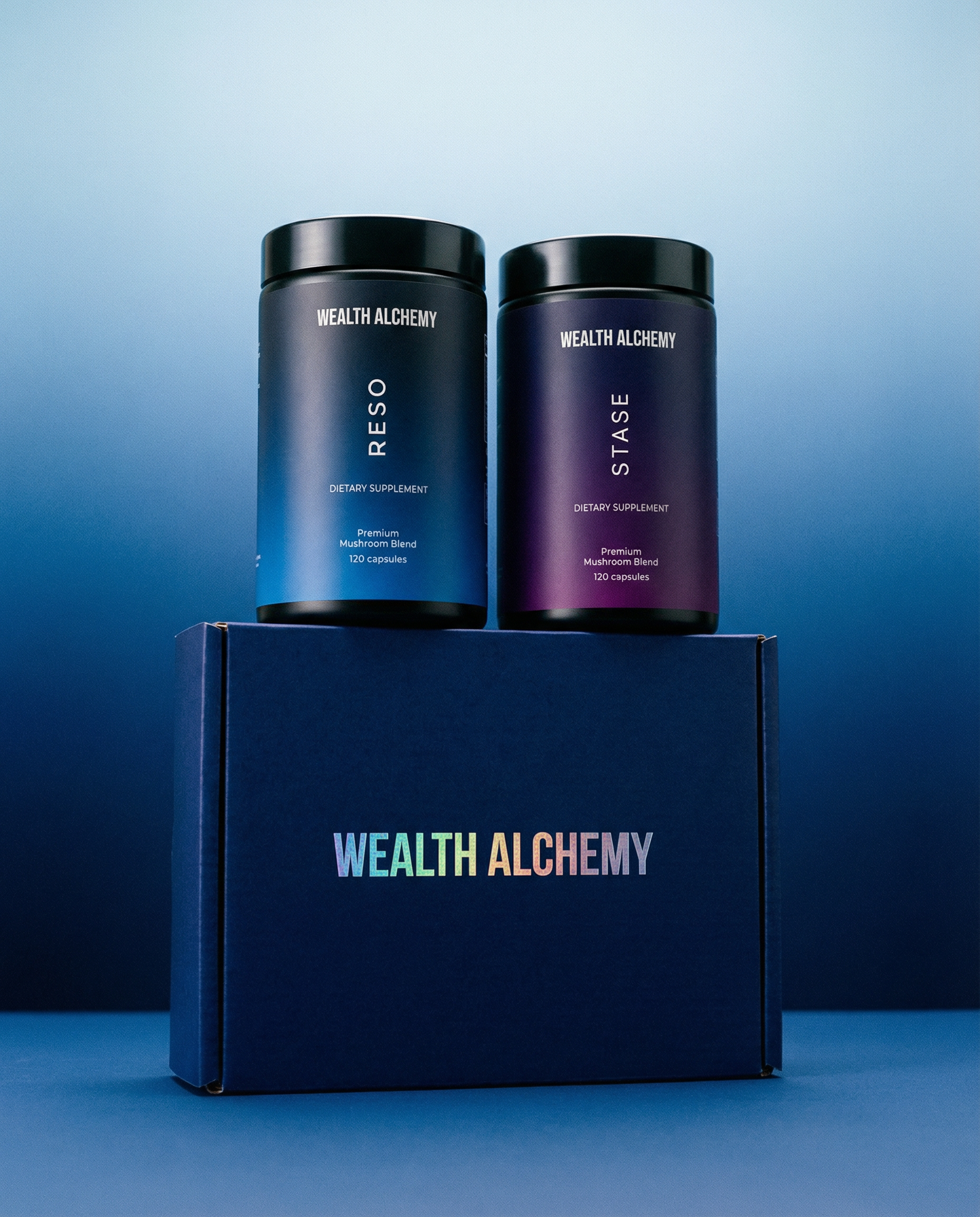 Two bottles of Wealth Alchemy dietary supplements, Reso and Stase, sitting on top of a branded blue box.