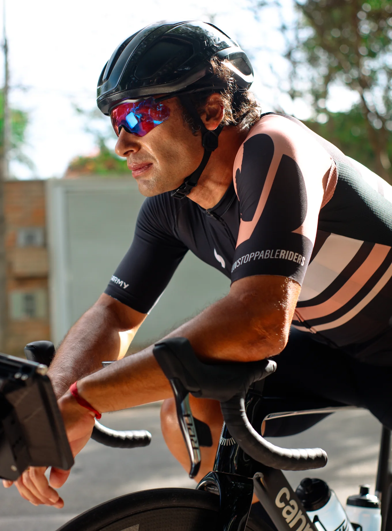Cyclist wearing a helmet and sunglasses, riding a bicycle outdoors.