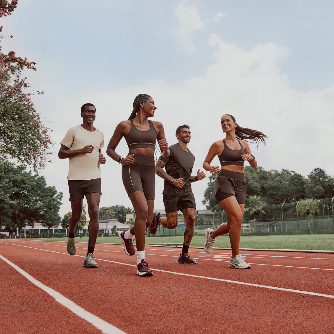 Four people jogging on a track under a partly cloudy sky.