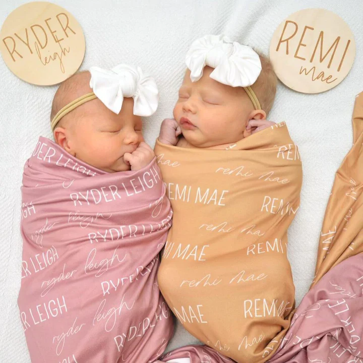 Two swaddled babies with headbands, labeled 'RYDER LEIGH' and 'REMI MAE'.
