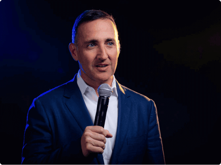 Person in a blue suit holding a microphone on stage.