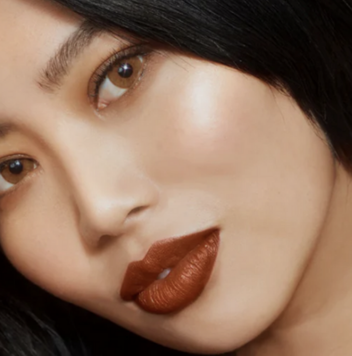 Close-up of a person's face with dark hair and bold lipstick.