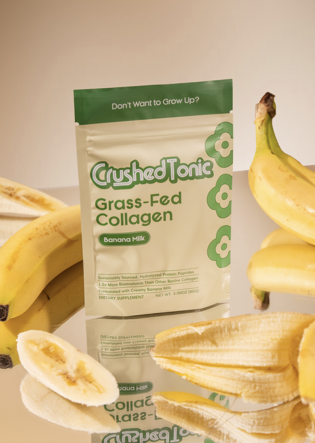 A packet of Crushed Tonic grass-fed collagen with bananas on a reflective surface.