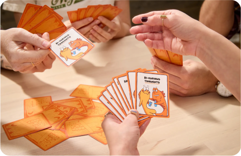 People playing a card game with cartoon animals on the cards.