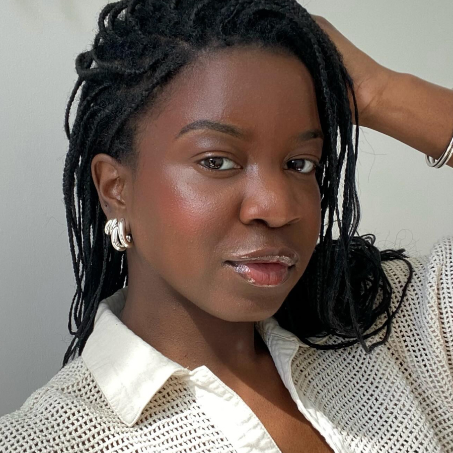 Person with braided hair, wearing a light shirt and silver earrings.