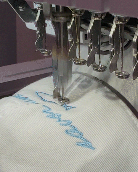 Embroidery machine stitching blue design on white fabric.