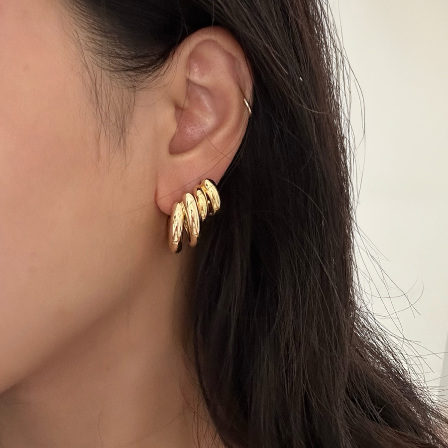 Close-up of ear with gold hoop earrings.