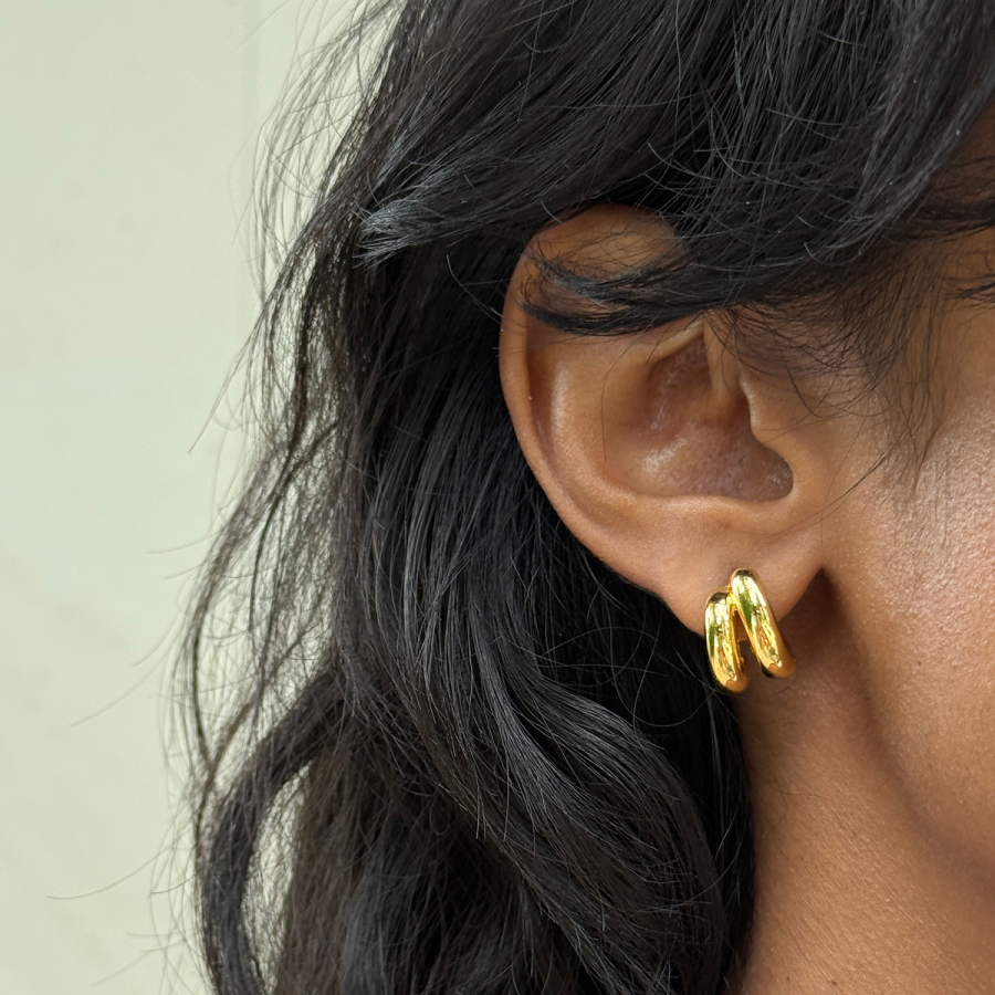 Close-up of an ear wearing gold hoop earrings.