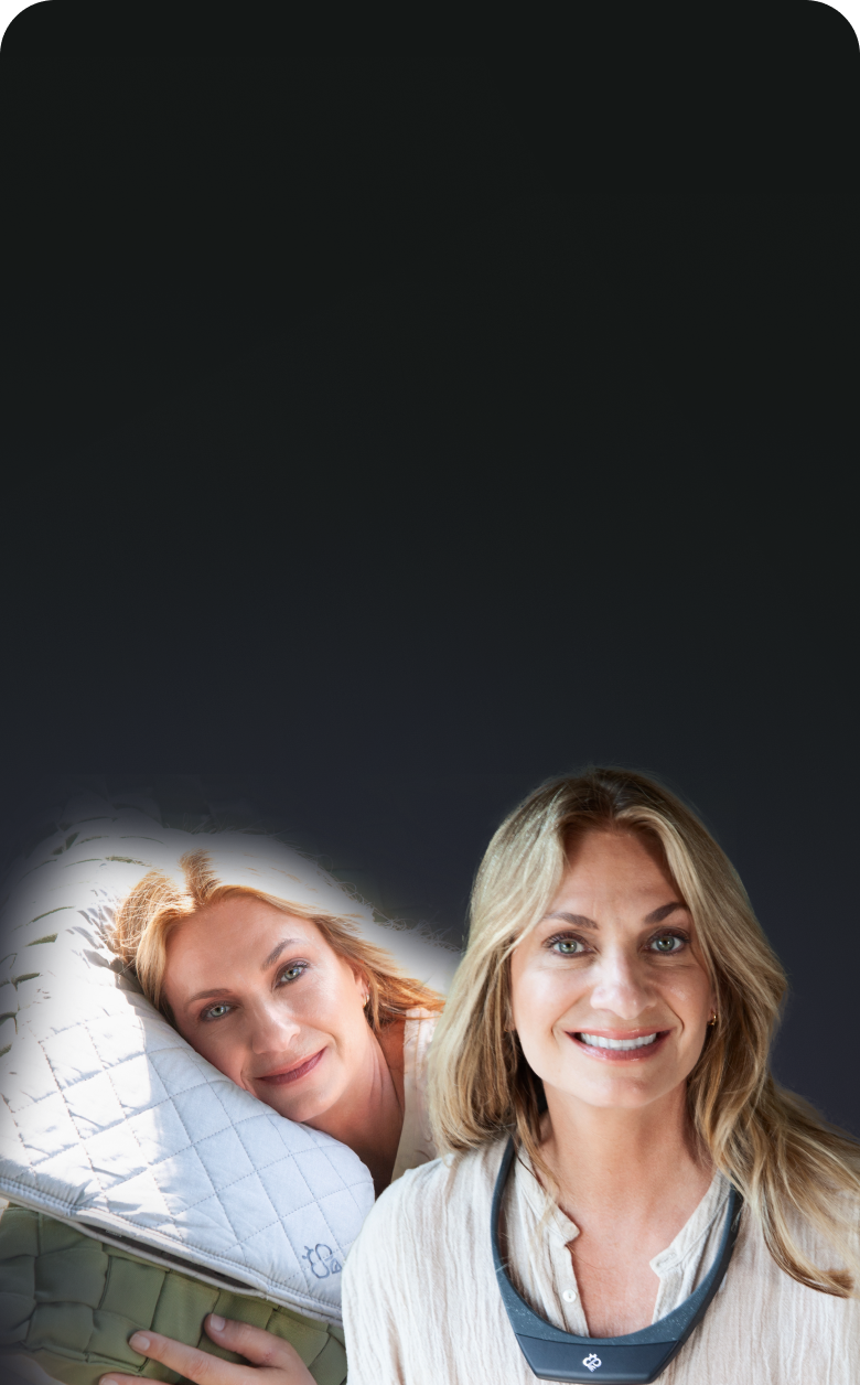 Two women smiling, one lying on a pillow, the other wearing a device around her neck.