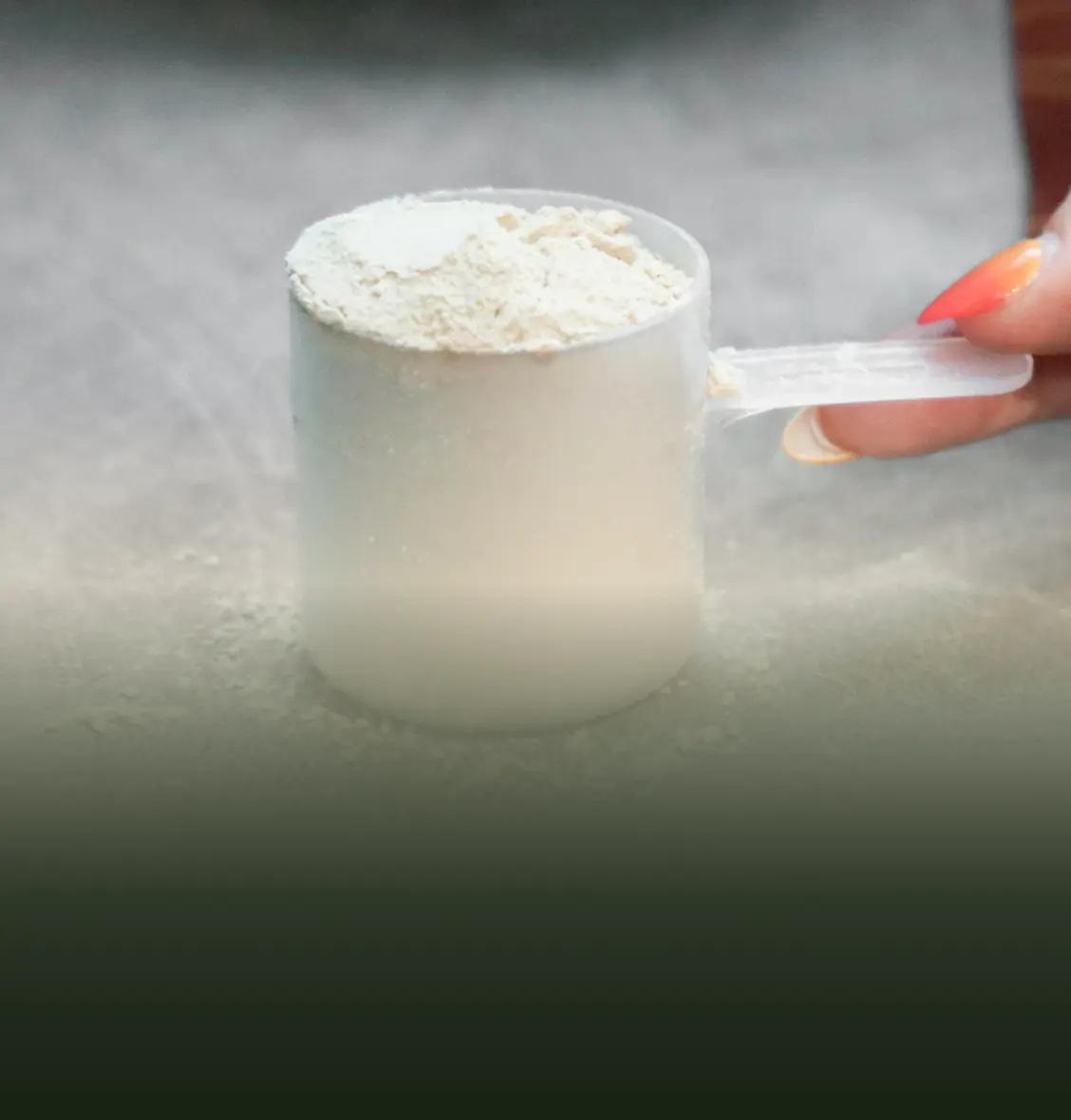 A hand holding a scoop of white powder on a surface.