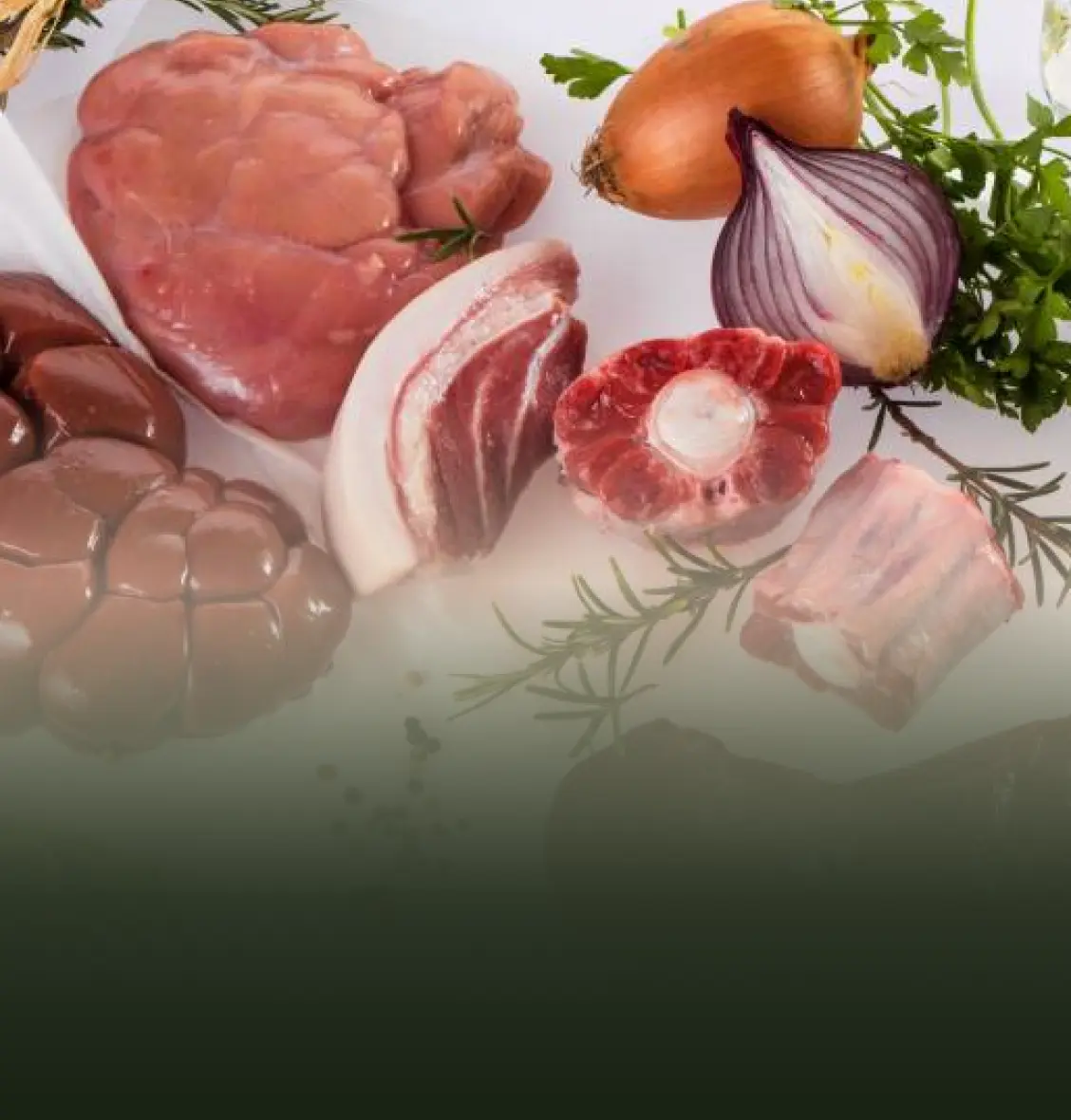 Assorted raw meats and vegetables on a white surface.