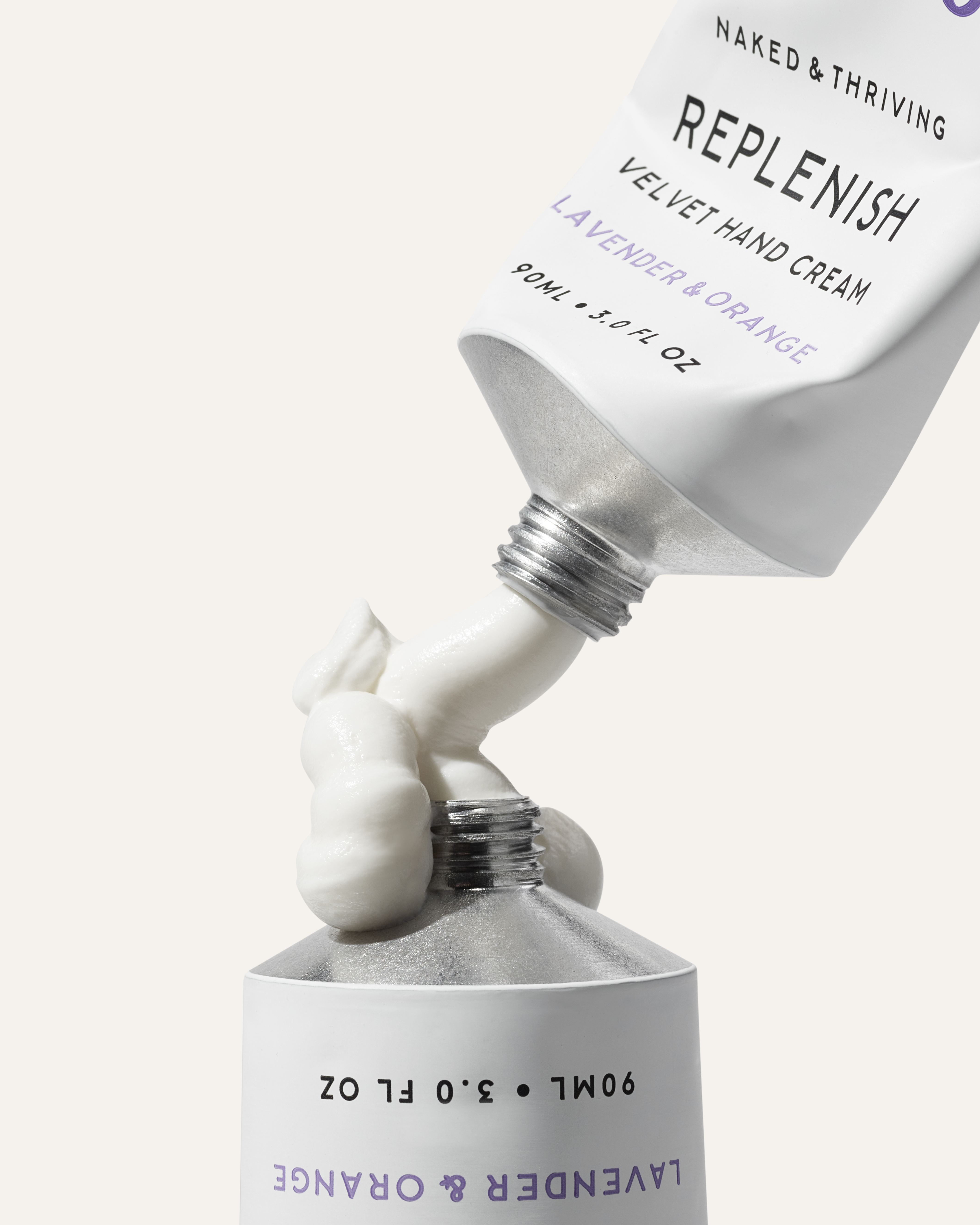 A tube of Naked & Thriving hand cream is squeezed onto the top of another tube.