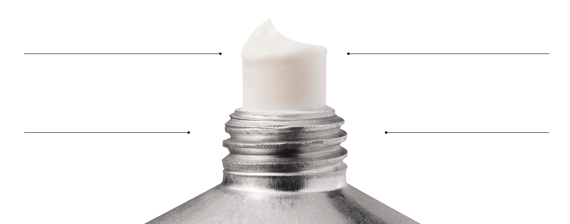 A close-up of white cream coming out of the tip of a metal tube.