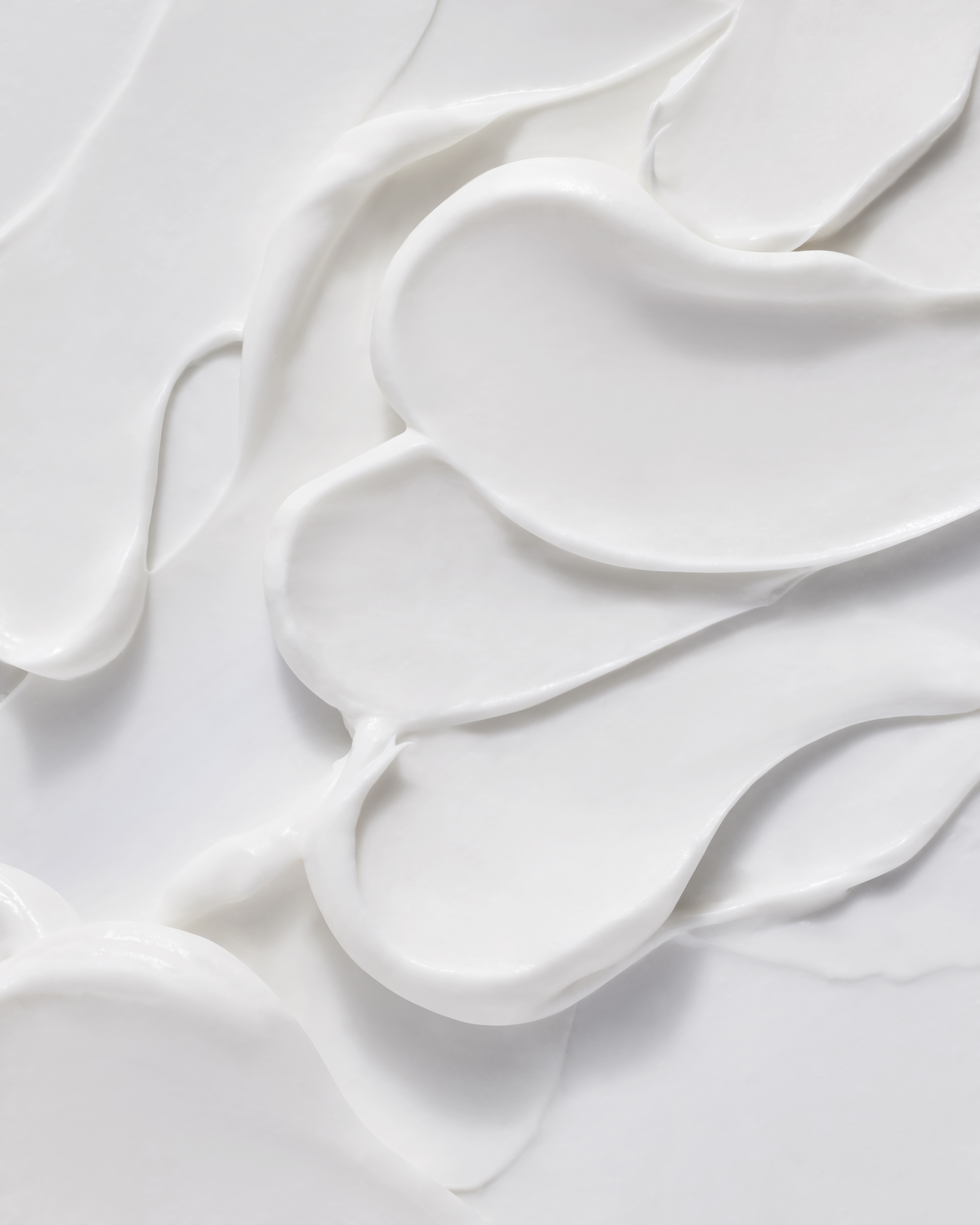 A close-up, top-down view of thick, white cream swirled and smeared across a surface.