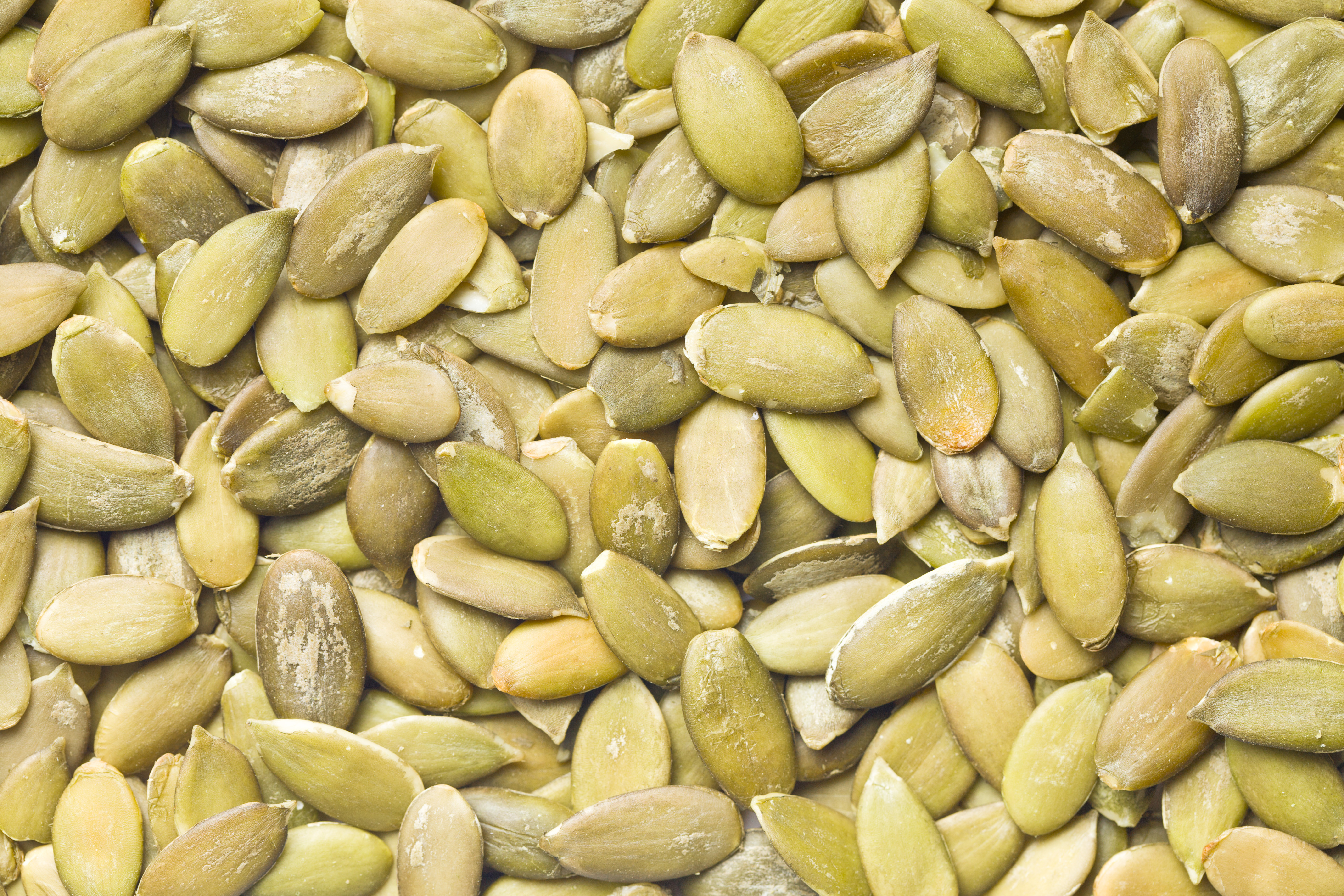 Close-up of raw pumpkin seeds, various shades of green.