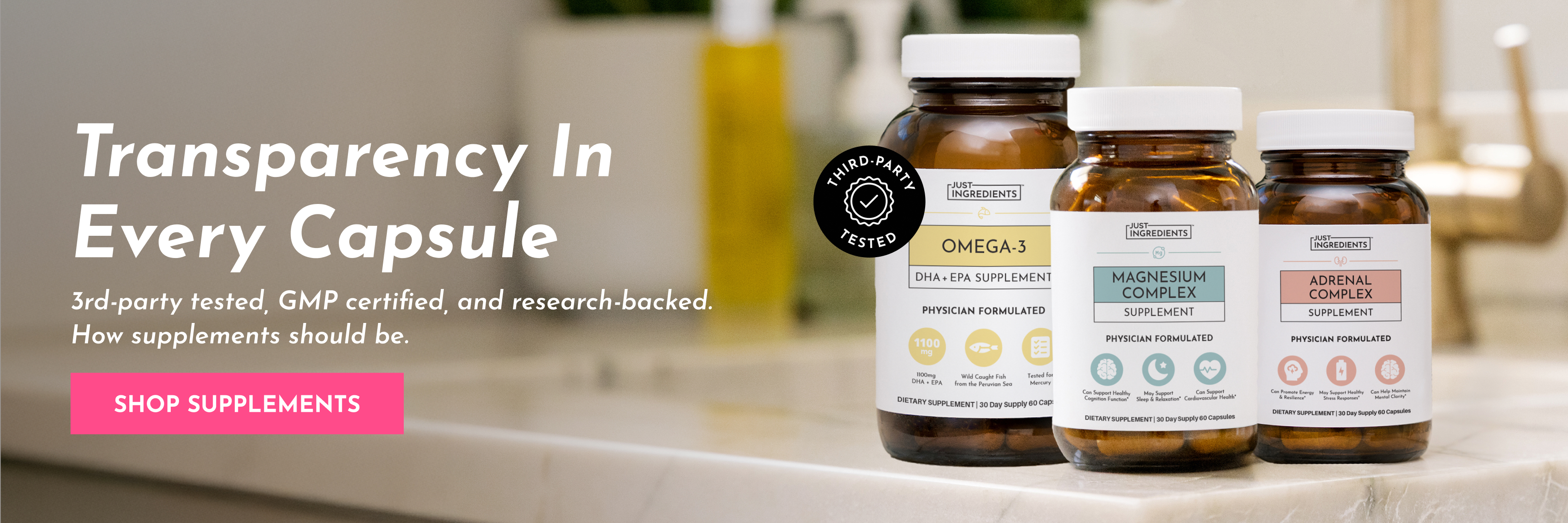 Three bottles of Just Ingredients brand supplements sitting on a marble countertop in a bathroom.