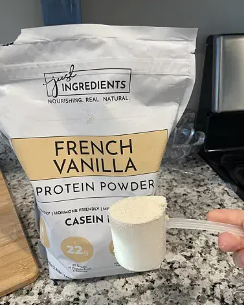 Bag of French vanilla protein powder with a scoop being held.