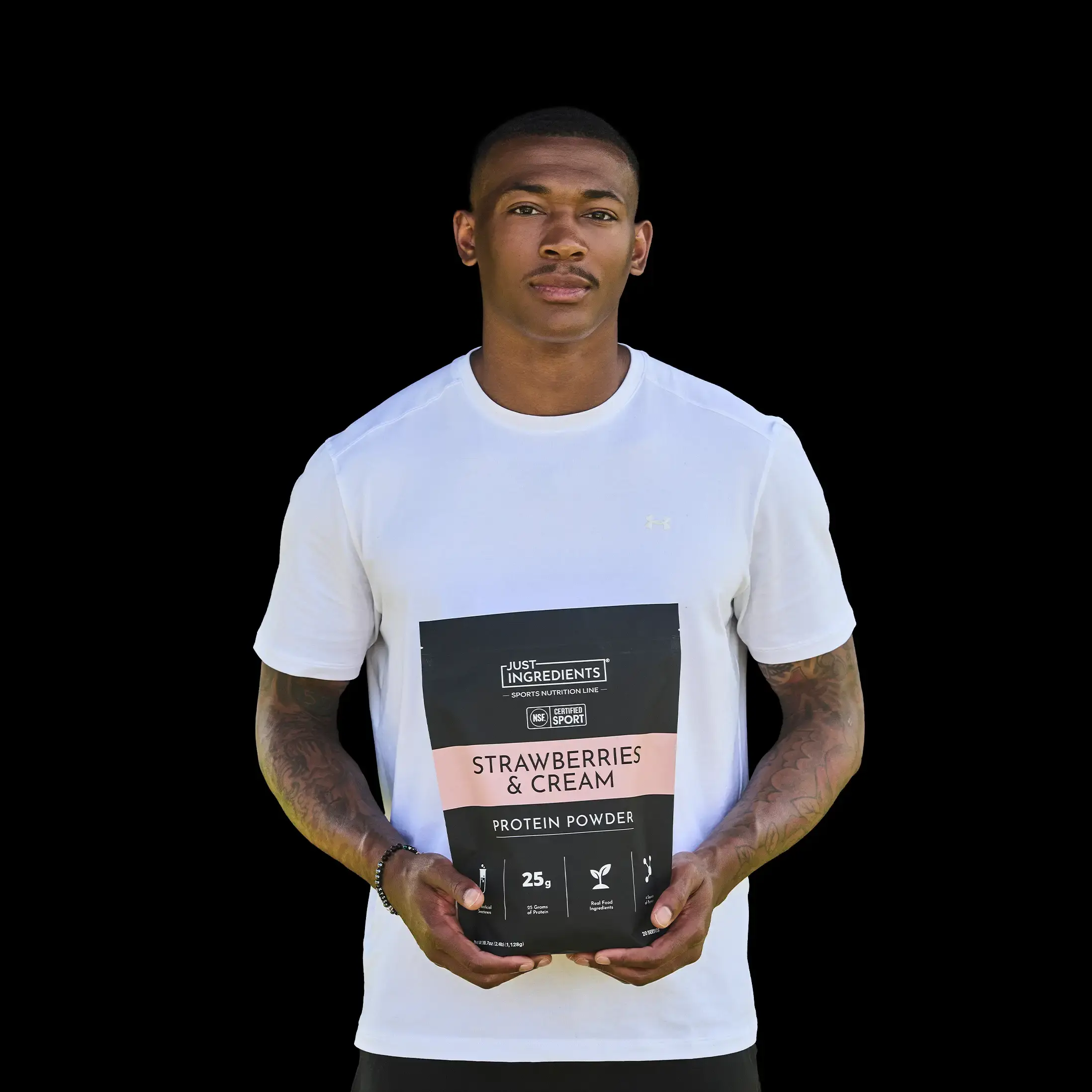 A man in a white t-shirt holds a bag of Just Ingredients Strawberries & Cream Protein Powder.