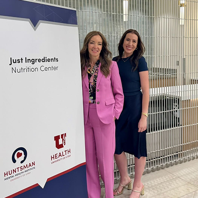 Two women standing beside a sign for the Just Ingredients Nutrition Center.