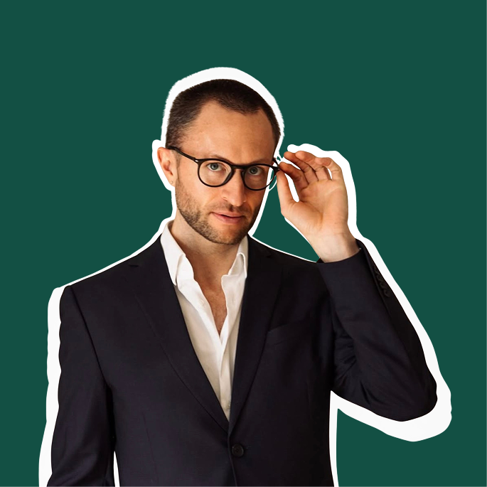 Person in a suit adjusting glasses against a green background.