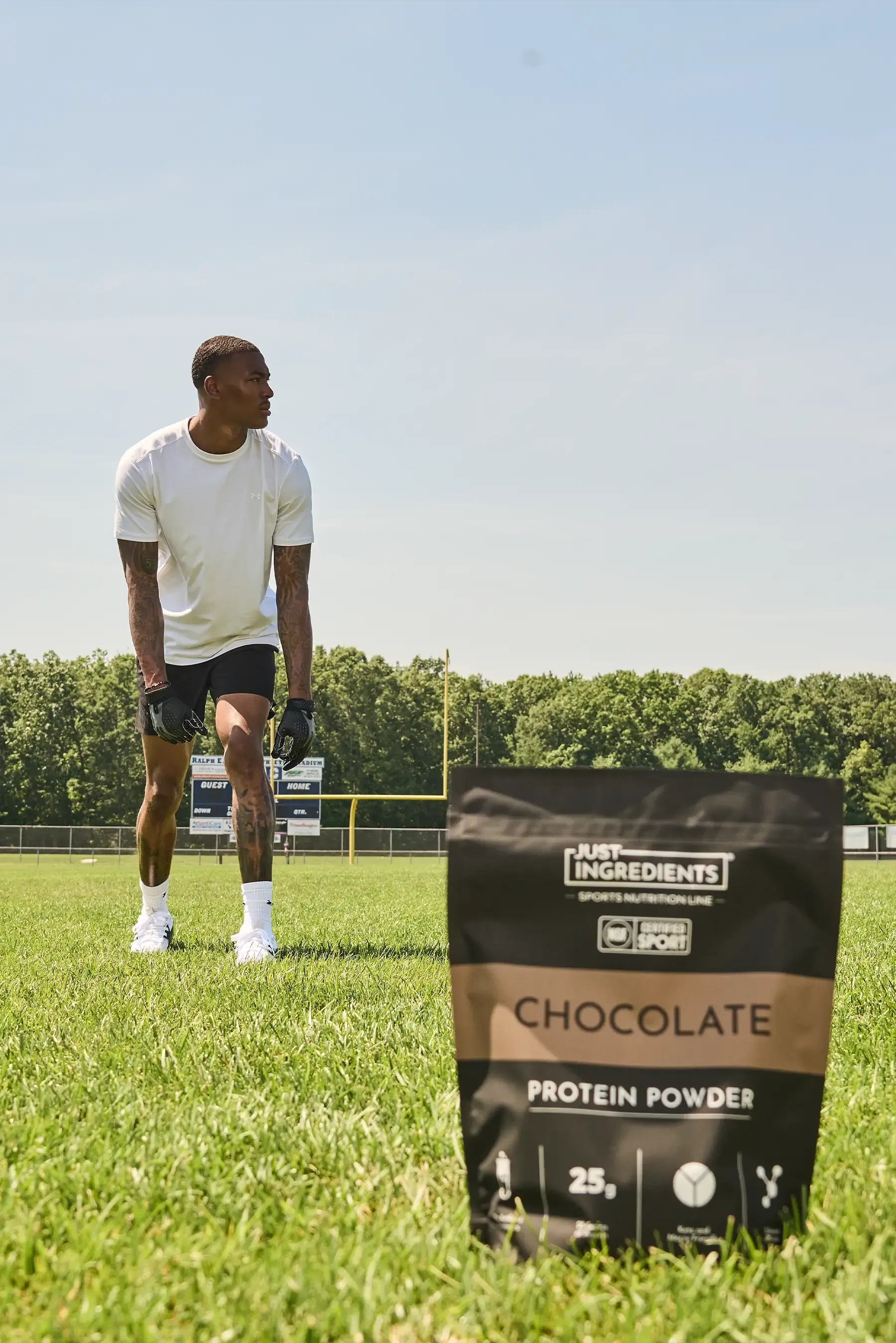 A man on a football field with a bag of Just Ingredients protein powder in the foreground.