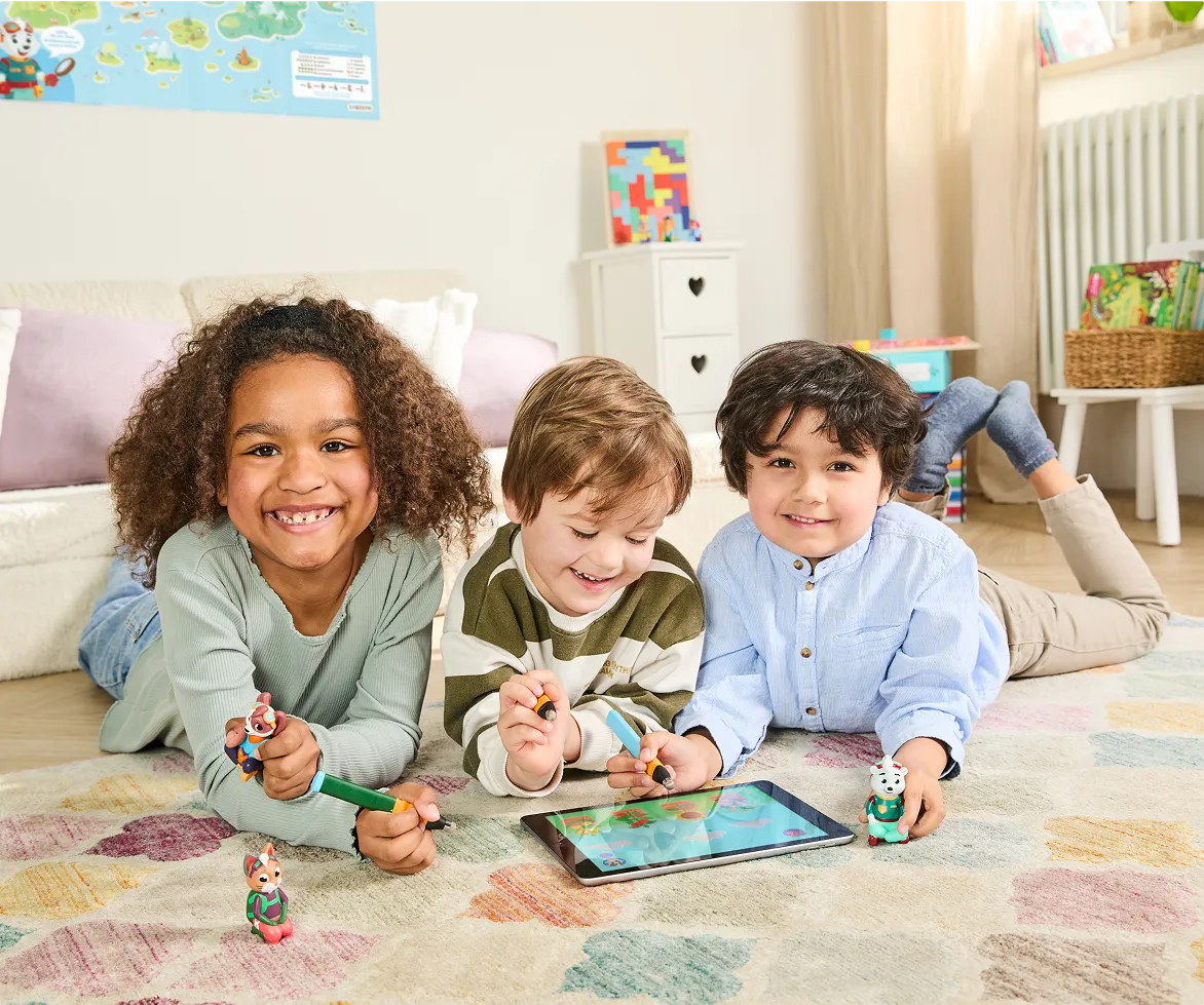Three children playing with a tablet and toys on a colorful rug.