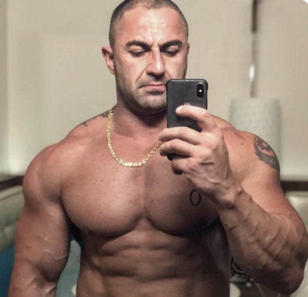 Muscular man taking a mirror selfie with a smartphone.
