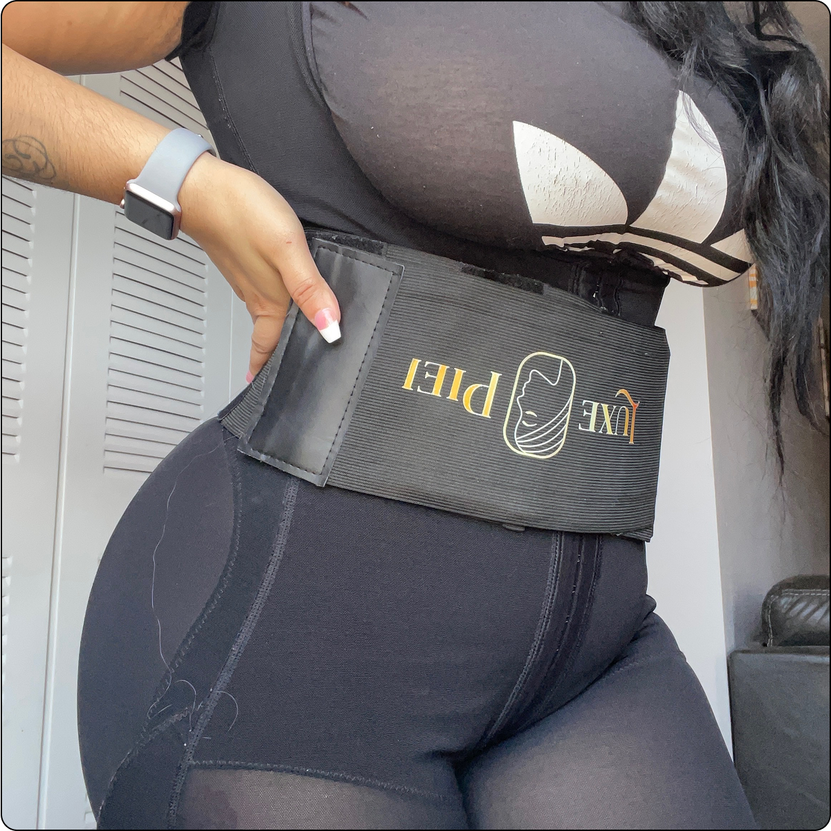 Person wearing a black waist trainer and black outfit, hand on hip.