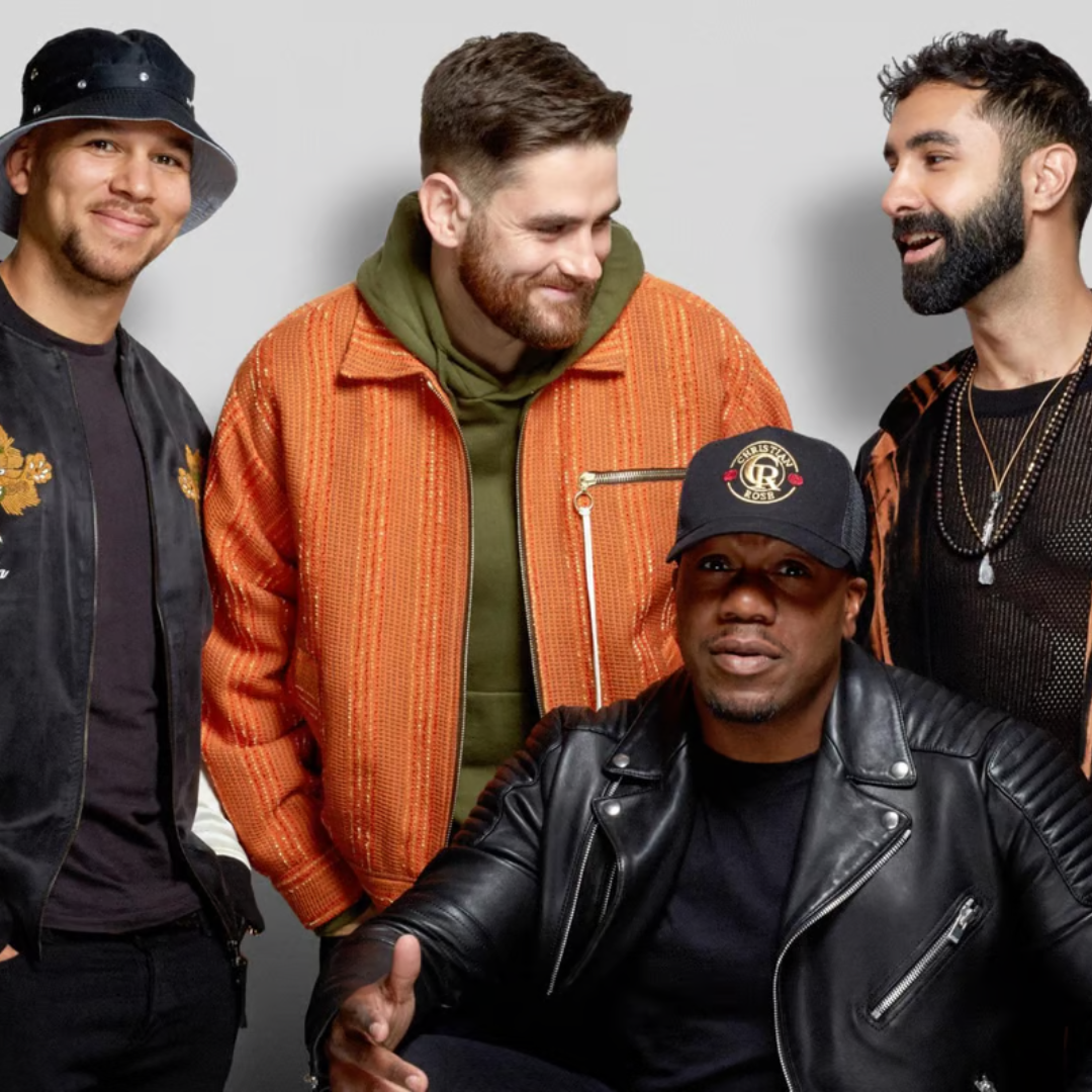 Four men in stylish casual clothing, smiling and interacting.