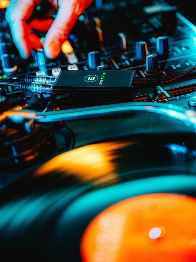 Close-up of a DJ's hand adjusting a mixer with a spinning vinyl record.