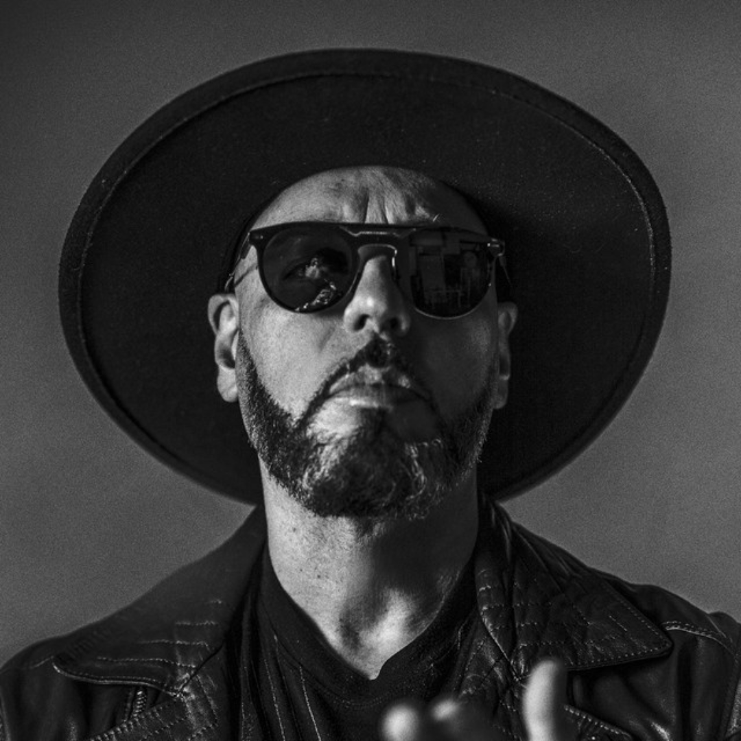 Black and white portrait of a man wearing sunglasses and a wide-brimmed hat.