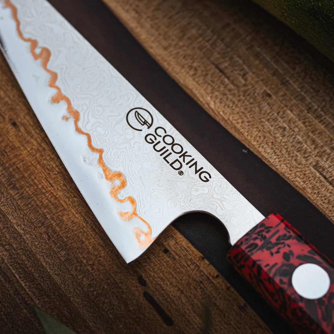 Close-up of a knife with 'Cooking Guild' logo on a wooden surface.