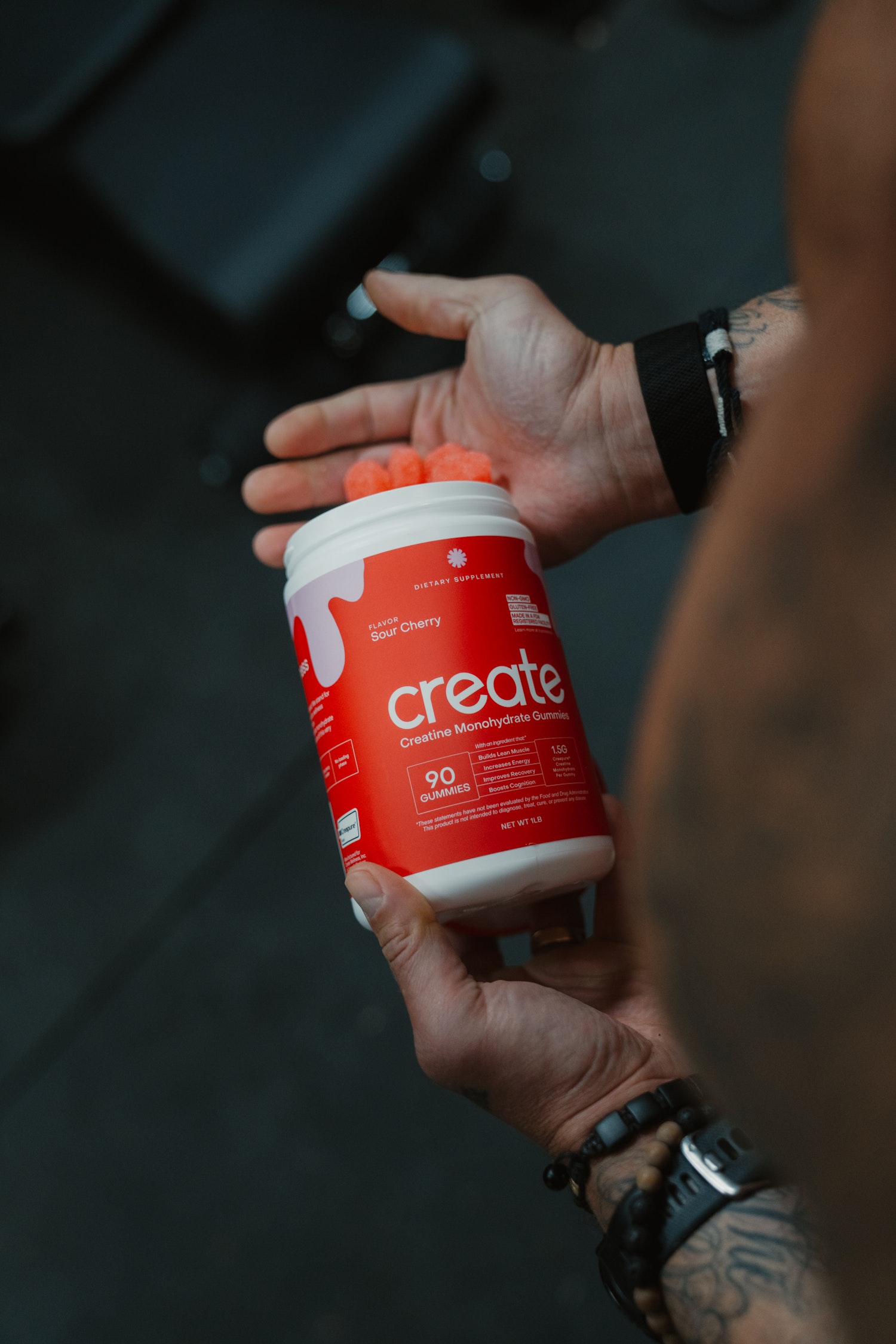 Person holding a container of creatine monohydrate gummies.