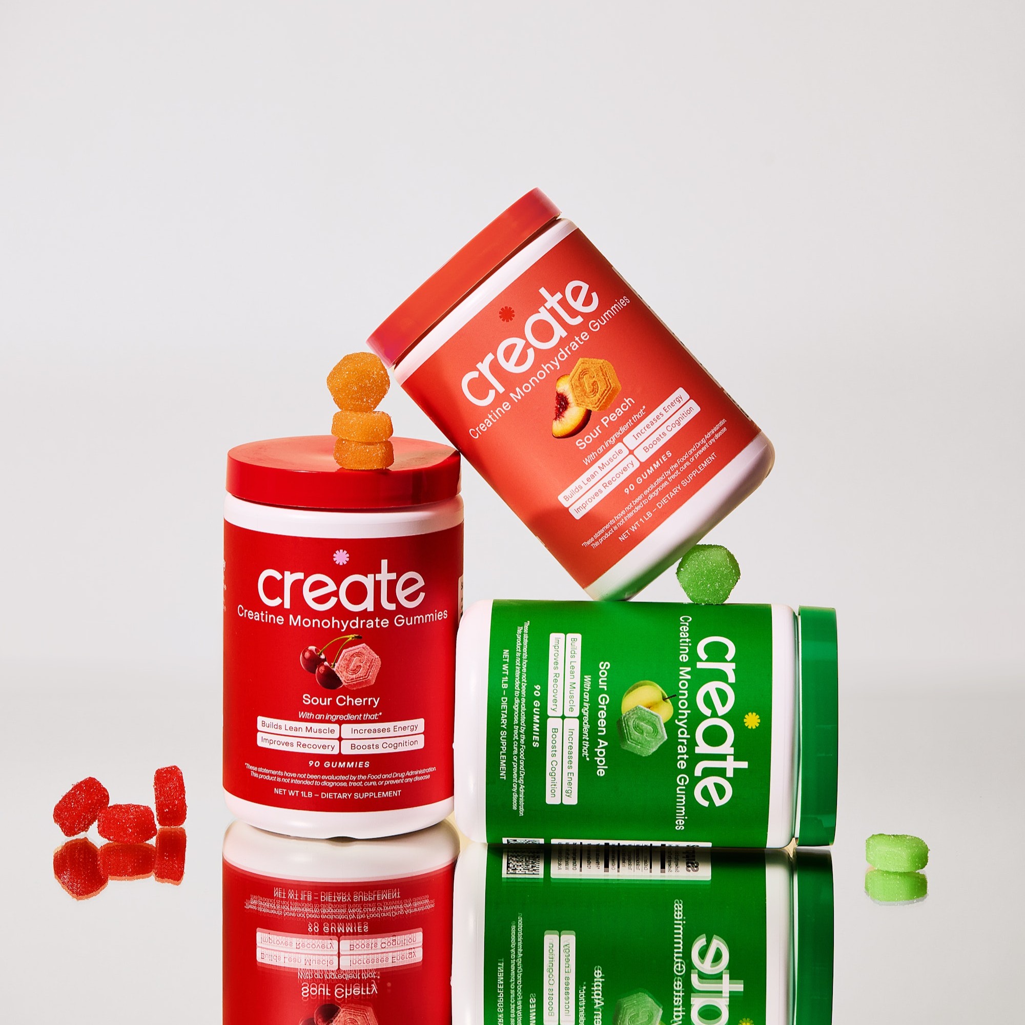 Three creatine gummy containers in red, orange, and green with stacked gummies.