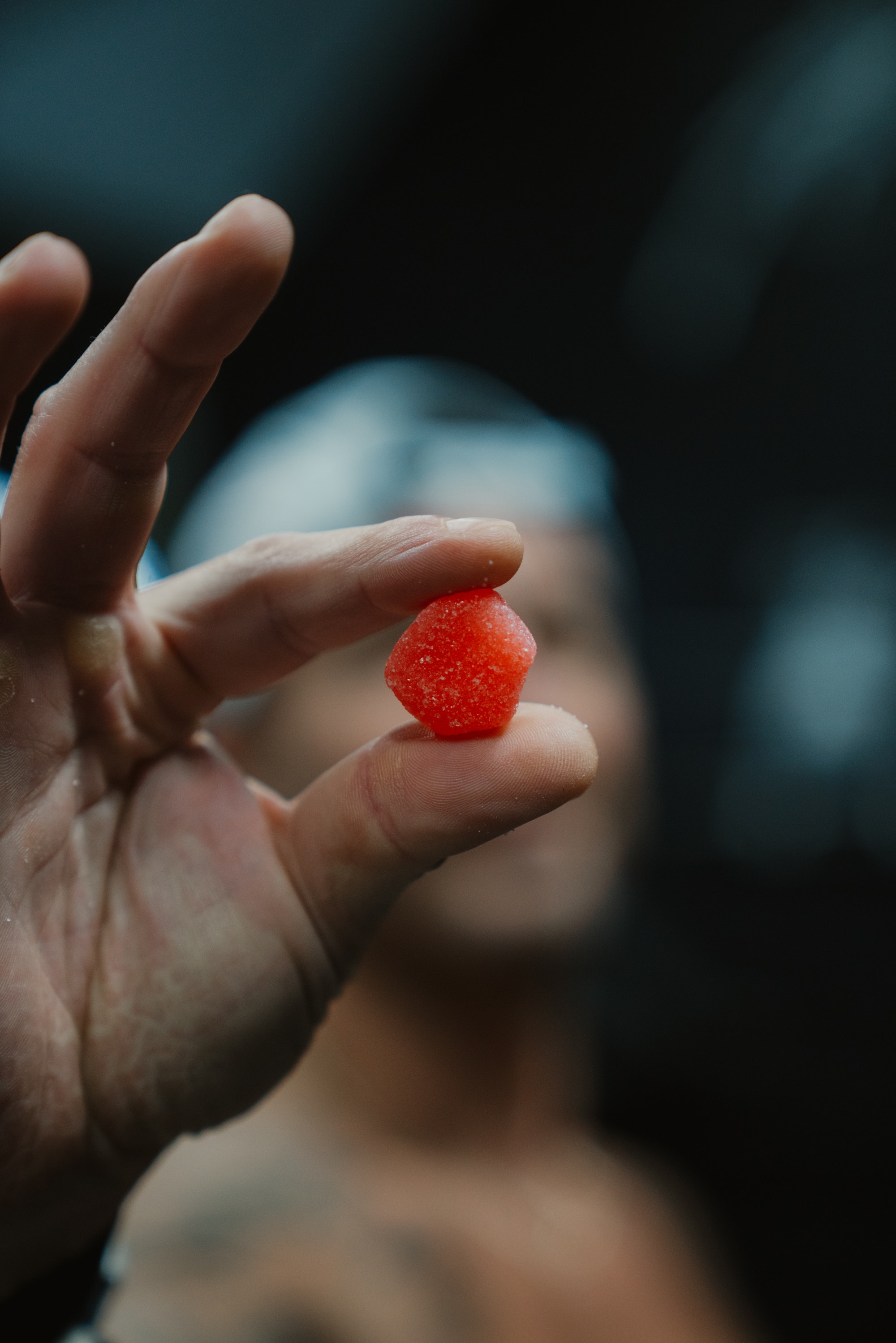 Close-up of a hand holding a small red candy.