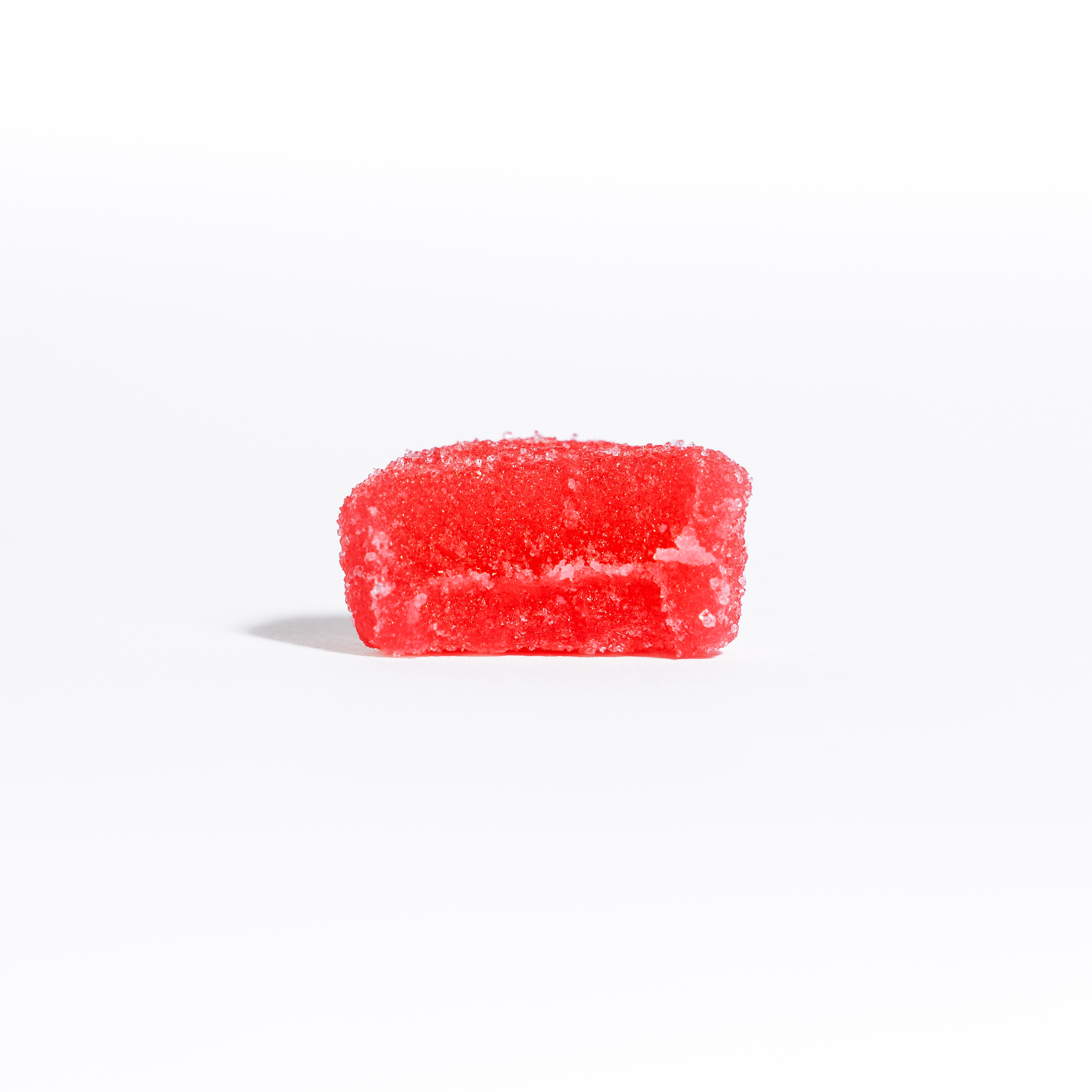 Hand holding a small hexagonal object against a green background.