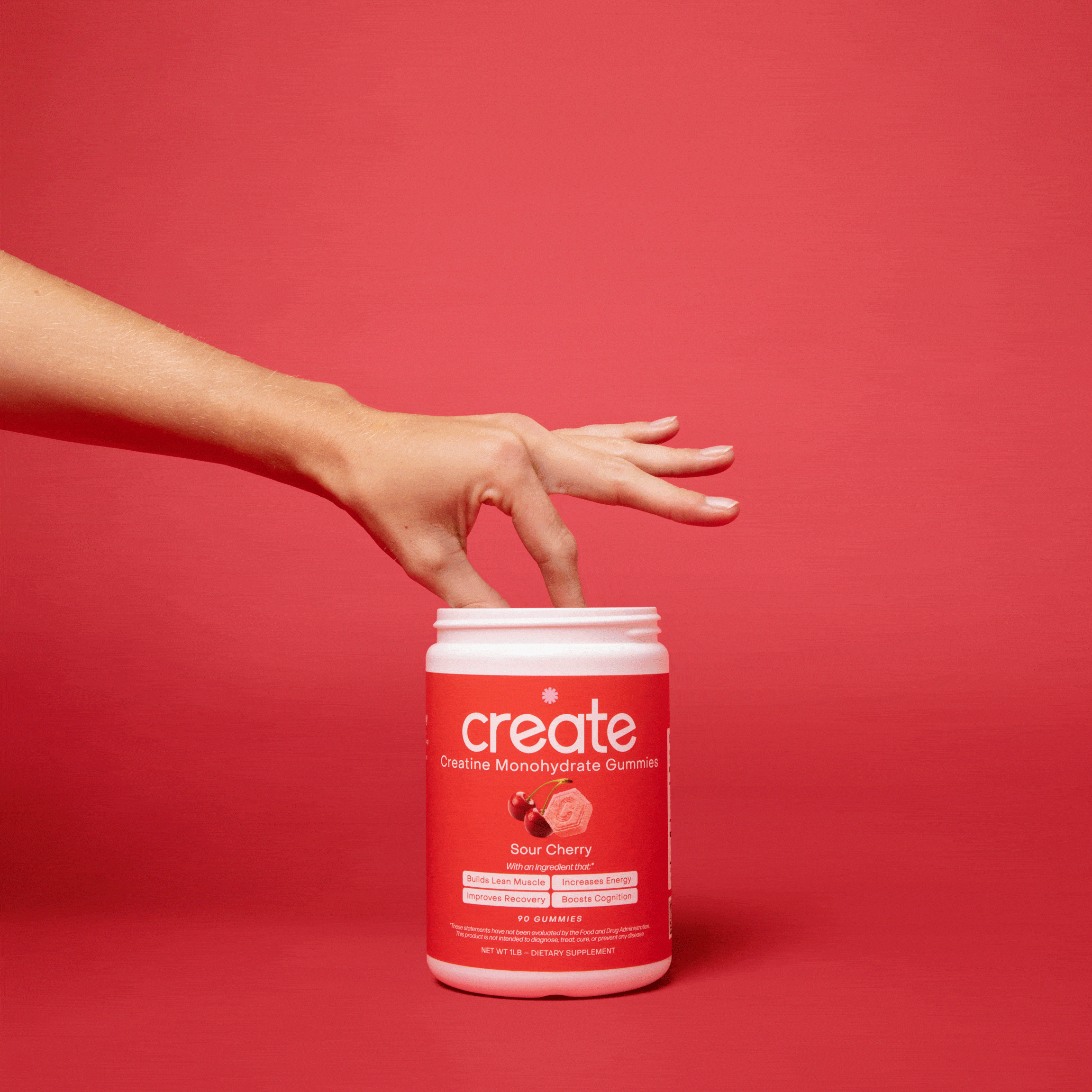 Hand reaches into a jar of creatine monohydrate gummies against a red background.