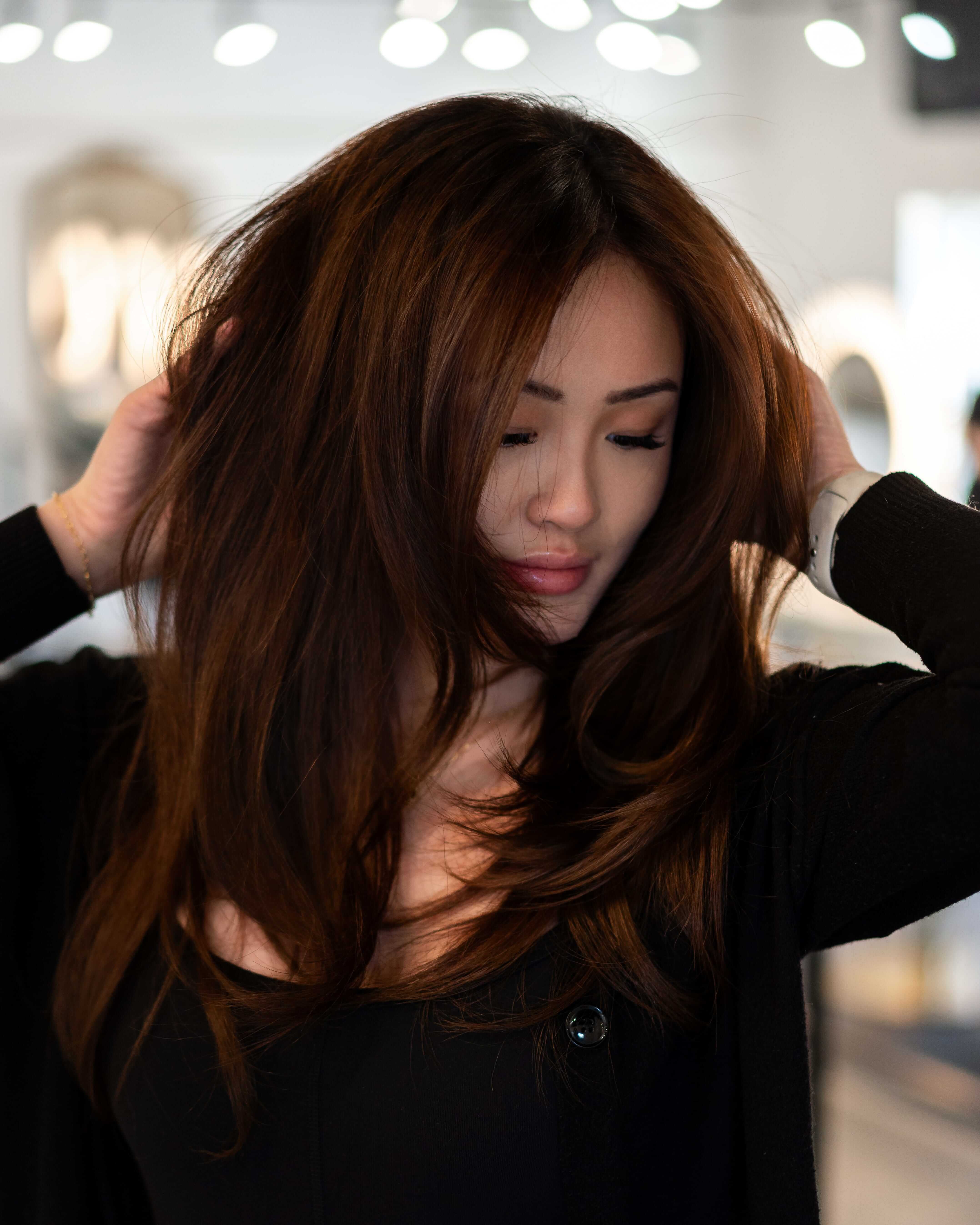 Brunette client admiring her silky, natural-looking Bello Haven hair extensions
