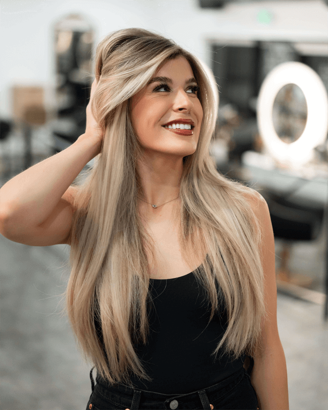 Woman with long blonde hair smiling in a salon.