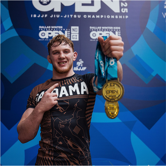 Person holding two gold medals at a jiu-jitsu championship event.